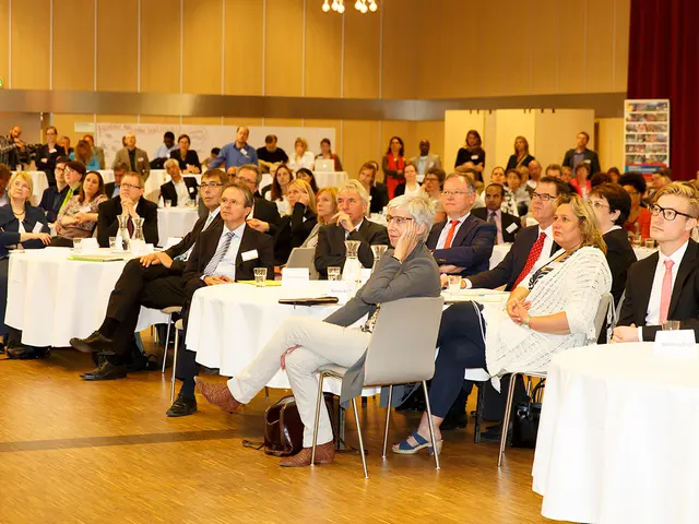 People are sitting in groups at tables and listening to something.