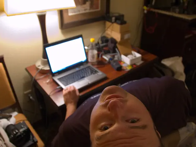 Sitting in the chair and working in the laptop and there is a lamp in front of him he is is tilted...