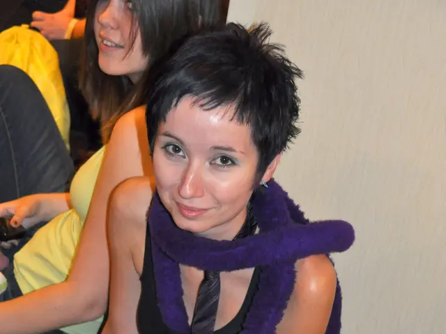 In the image few women are sitting and smiling. Behind them there is a wall.