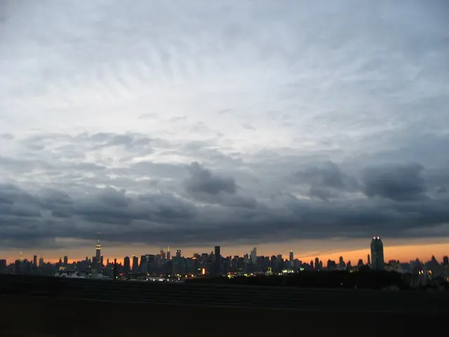 This image consists of many buildings and skyscrapers. At the top, there are clouds in the sky. At...